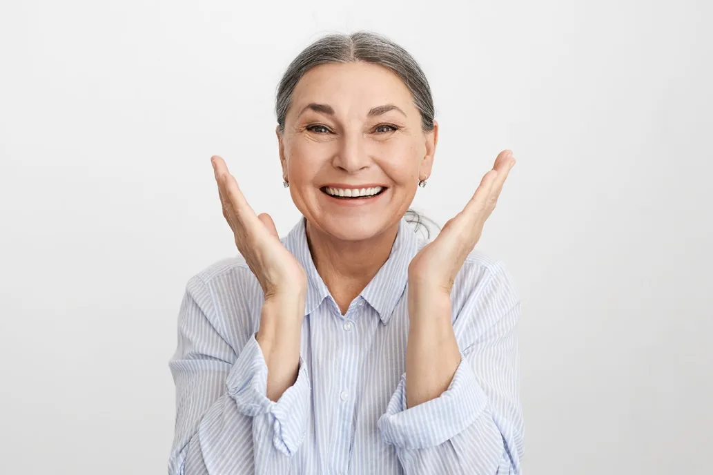 A woman raising both hands, delighted with her new full-arch smile